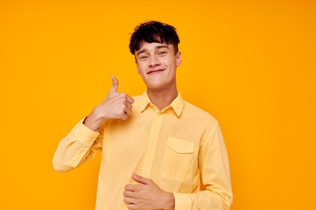 Vrolijke jonge man in een geel shirt gebaren met zijn handen emoties