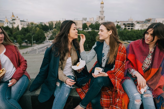 Vrolijke jonge meisjes die samen goede tijd doorbrengen. Goede vrienden die frietjes delen in café op het dak. Ongewone plaatsen voor rust en entertainment, vrije tijd met een vrolijk sfeerconcept