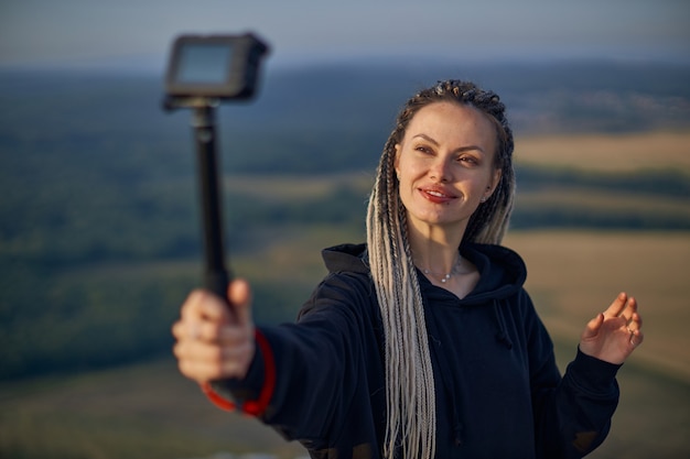 Foto vrolijke jonge meisjesblogger neemt een selfie, neemt foto's van zichzelf op de camera en heeft een leuke stand...