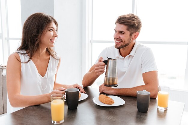 Vrolijke jonge paar koffie drinken met croissants op de keuken