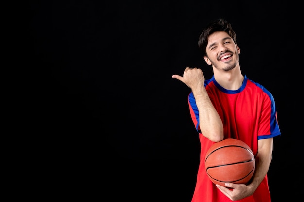 Vrolijke jonge speler met basketbal op zwart