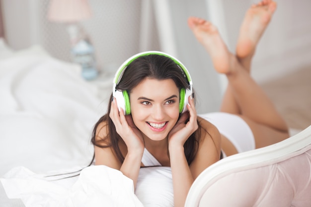 Vrolijke jonge vrouw die aan de muziek luistert. Mooi meisje dat oortelefoons draagt