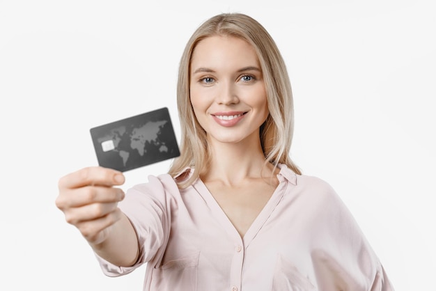 Vrolijke jonge vrouw die creditcard toont die over witte achtergrond wordt geïsoleerd