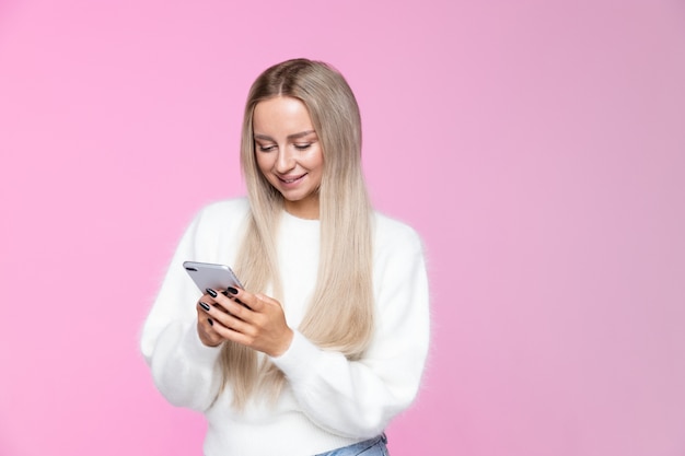 Vrolijke jonge vrouw die en mobiele telefoon glimlacht gebruikt