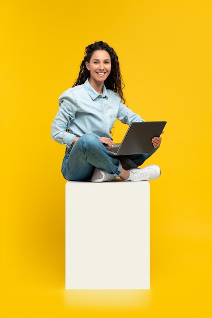 Vrolijke jonge vrouw die laptop met behulp van bij studio