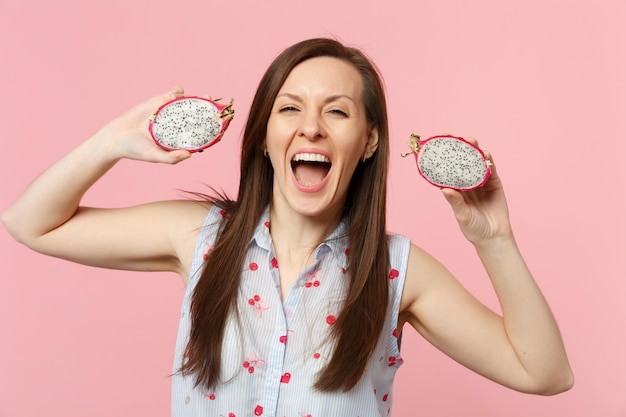 Vrolijke jonge vrouw die mond open houdt met verse rijpe pitahaya's, drakenfruit geïsoleerd op roze pastelmuurachtergrond in studio. Mensen levendige levensstijl ontspannen vakantie concept. Bespotten kopie ruimte.