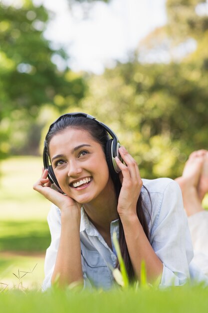 Vrolijke jonge vrouw die van muziek in park geniet