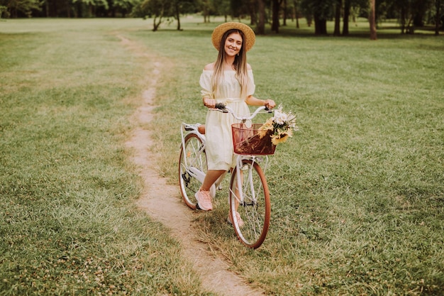 Vrolijke jonge vrouw fietst door het veld