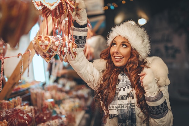 Vrolijke jonge vrouw heeft plezier op een kerstmarkt in de stadsstraat op de nieuwjaarsnacht.