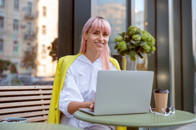 Vrolijke jonge vrouw met behulp van laptop op outdoor cafe