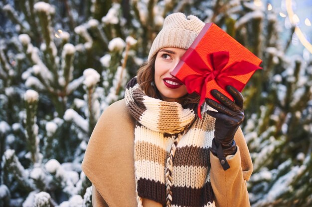 Vrolijke jonge vrouw met cadeau in de winter