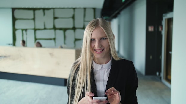 Vrolijke jonge vrouw met telefoon in office.