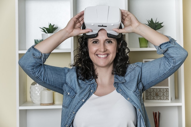 Vrolijke jonge vrouw met virtual reality bril in lichte hedendaagse kantoor
