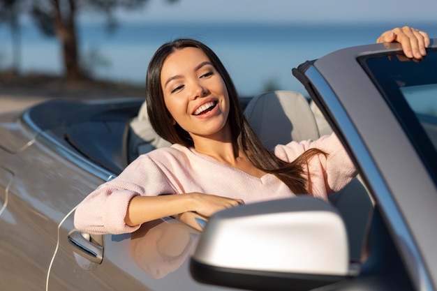 Vrolijke jonge vrouw op zoek vanuit cabrio