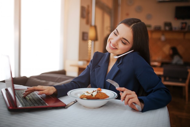 Vrolijke jonge vrouw zitten aan tafel in restaurant