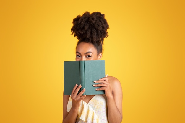 Vrolijke jonge zwarte vrouw leesboek heeft alleen plezier