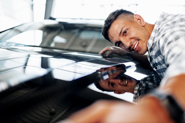 Foto vrolijke jongeman klant koopt een nieuwe auto bij een dealer
