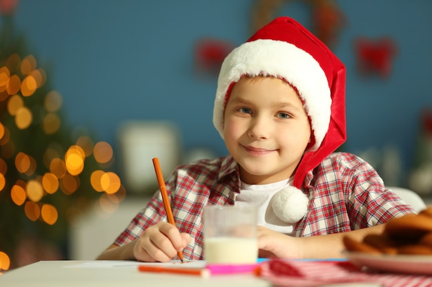 Vrolijke jongen die een brief schrijft aan de kerstman