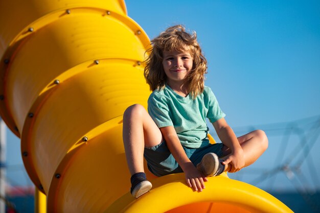 Vrolijke jongen die plezier heeft op de speelplaats buiten grappig kindergezicht