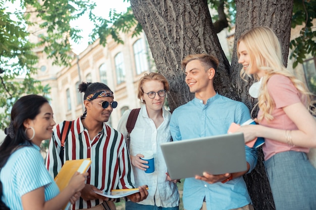 vrolijke jongen die zich onder zijn groepsgenoten met laptop bevindt