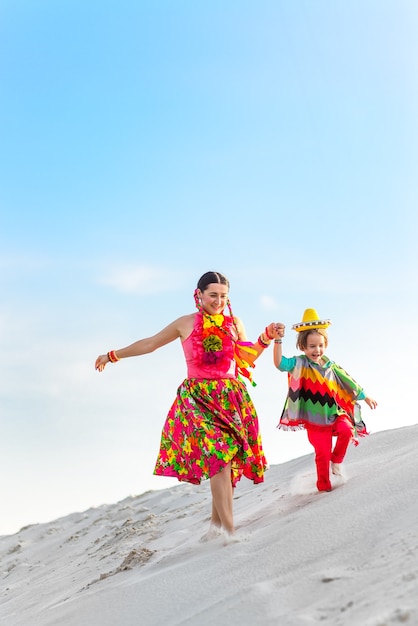 Vrolijke jongen en zijn gelukkige moeder die op zand lopen.