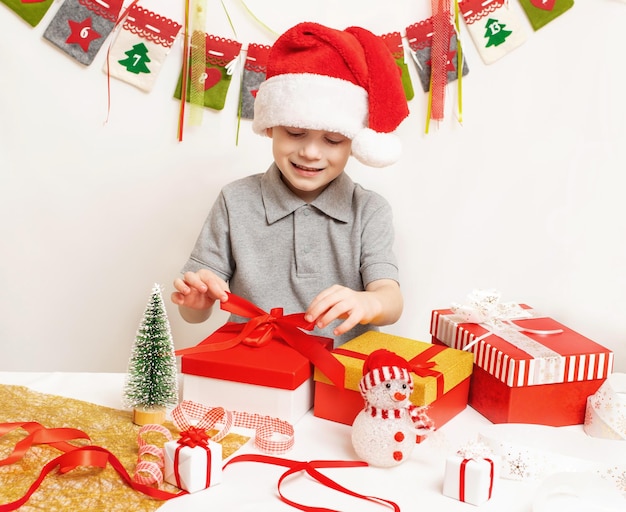 Vrolijke jongen in hoed Kerstman die cadeaus voor kerst thuis voorbereidt Kerstfamilietradities Gezellig vakantie-interieur