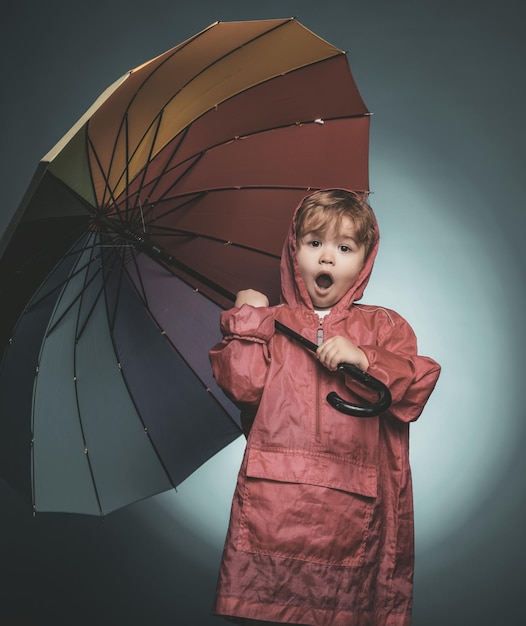 Vrolijke jongen in regenjas met kleurrijke paraplu glimlachend jongetje spelen met bladeren en kijken naar camera verkoop voor hele herfstcollectie ongelooflijke kortingen en geweldige keuze kid in regen