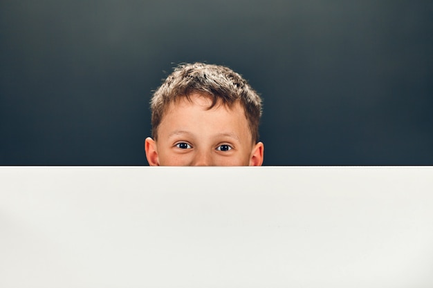 Vrolijke jongen kijkt uit van achter een spandoek