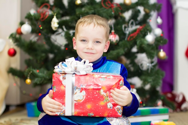 Vrolijke jongen met een cadeautje onder de kerstboom