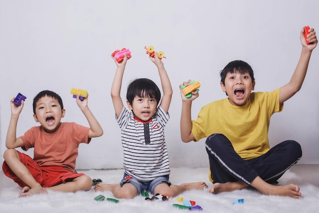 Vrolijke kinderen spelen met kleurrijke bakstenen en schreeuwen van vreugde op witte achtergrond