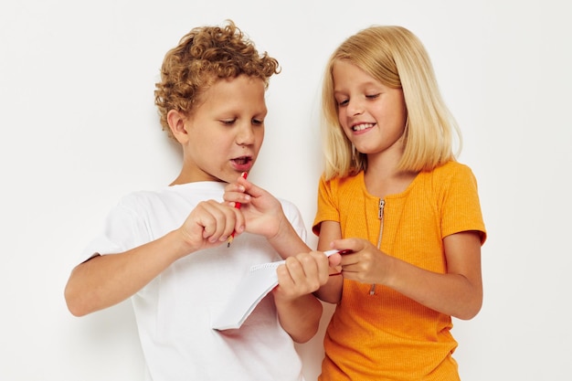 Vrolijke kinderen staan naast notitieblok potlood tekenen emoties kleur achtergrond ongewijzigd