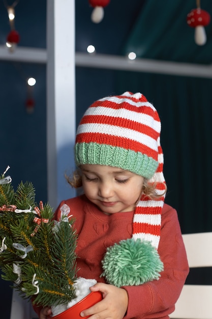 Foto vrolijke kleine meisjeskerstmuts met kleine kerstboomhanden