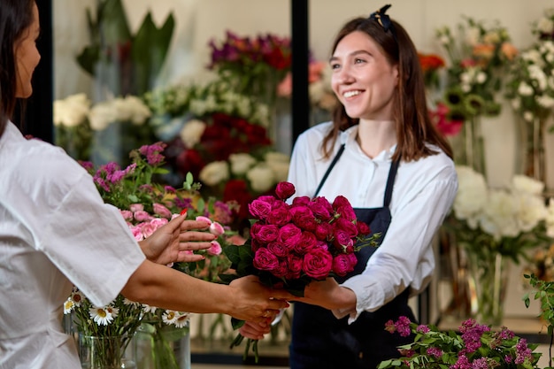 Vrolijke kleine ondernemer vrouw oranjerie eigenaar bloemen geven aan klant