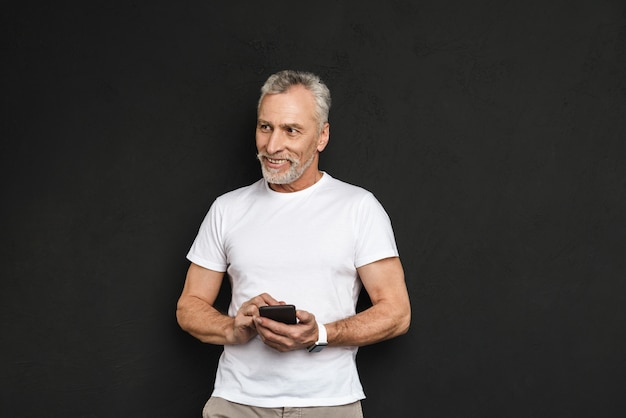 Vrolijke knappe volwassen oude man met behulp van mobiele telefoon.