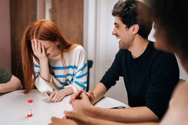 Vrolijke lachende multi-etnische vrienden die kaartspellen spelen om tijd te genieten van bordspellen thuis Vrolijke diverse mannen en vrouwen die spelen