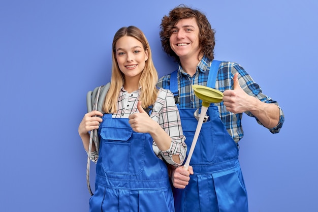 vrolijke man en vrouw loodgieters in blauw uniform met plunjer tool