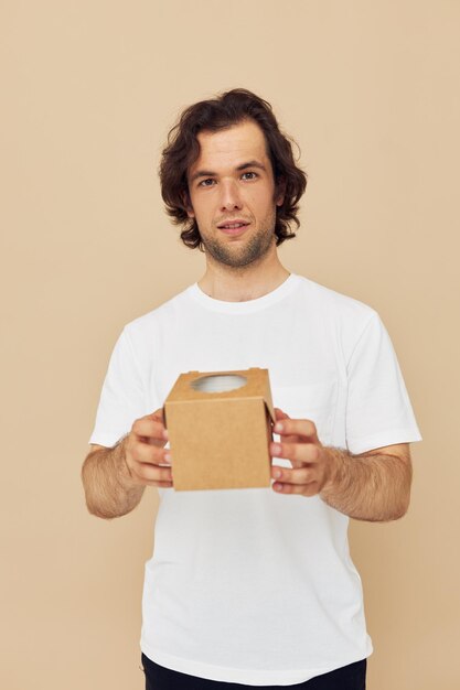 Vrolijke man in een wit t-shirt met een kartonnen doos in zijn handen