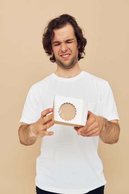 Vrolijke man in een wit t-shirt met een kartonnen doos in zijn handen