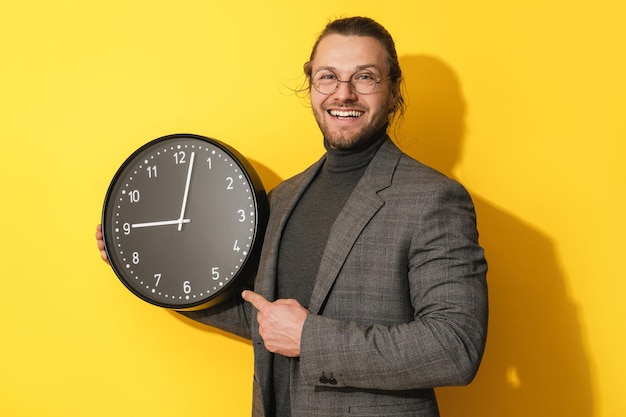 Vrolijke man met bril met grote klok op gele achtergrond