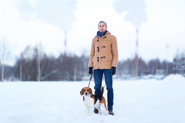 Vrolijke man met staan met een hond op een weide in de winter