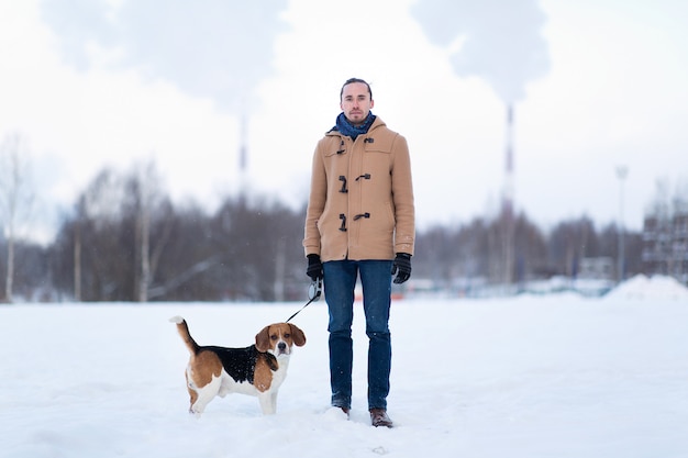 Vrolijke man met staan met een hond op een weide in de winter