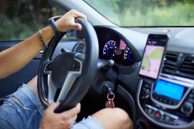 Vrolijke man rijdende auto met behulp van mobiele telefoon met kaart gps navigatie