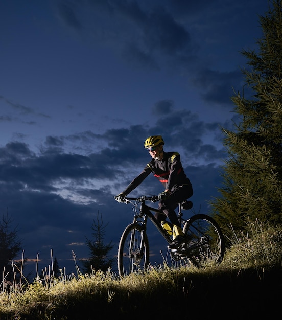 Vrolijke mannelijke wielrenner die 's nachts fietst