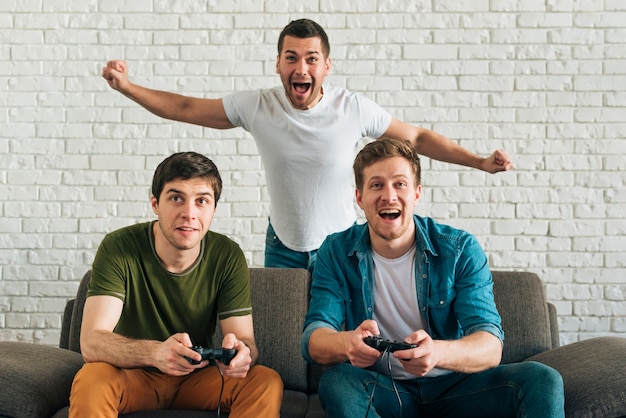 Foto vrolijke mens die voor de vrienden toejuichen die videospelletje thuis spelen