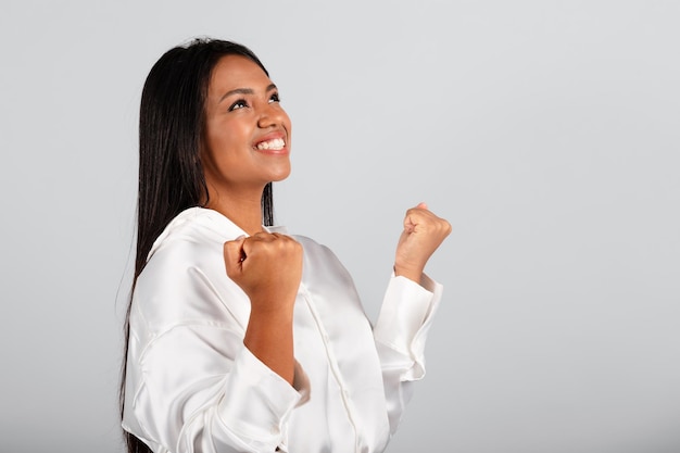 Vrolijke millennial zwarte zakenvrouw in witte blouse maken succes overwinning gebaar kijkend naar vrije ruimte