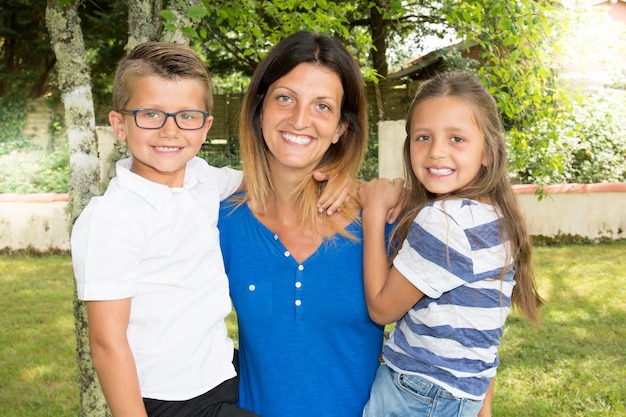 Vrolijke moderne de moederouder van de familie songle met twee kinderendochter en zoon onrms op de tuin van het huishuis