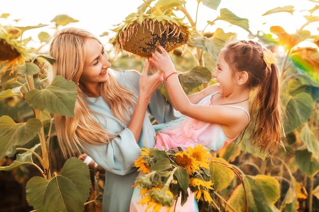 Vrolijke moeder en dochter maken een grote rijpe zonnebloem schoon