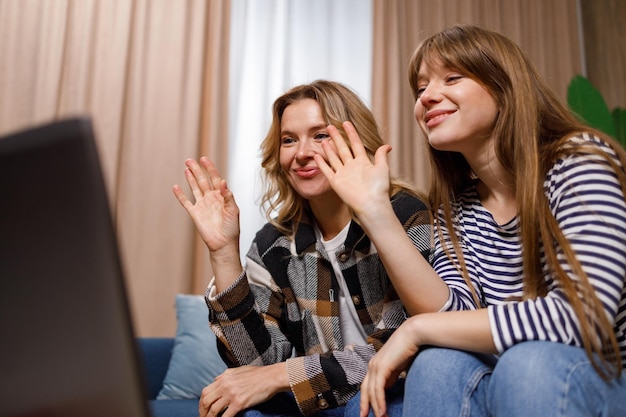 Vrolijke moeder en dochter zwaaien vriendelijk naar de laptop