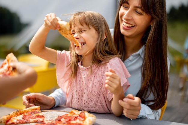 Vrolijke moeder met haar dochtertje pizza eten