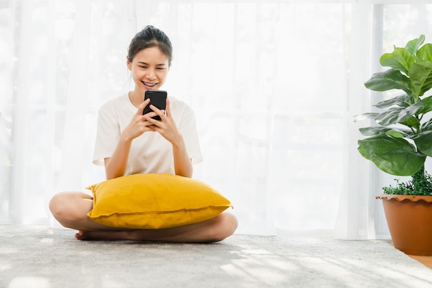 Vrolijke mooie Aziatische vrouw die een smartphone houden en online sociale media op levensstijl gebruiken. Technologie voor communicatieconcept.